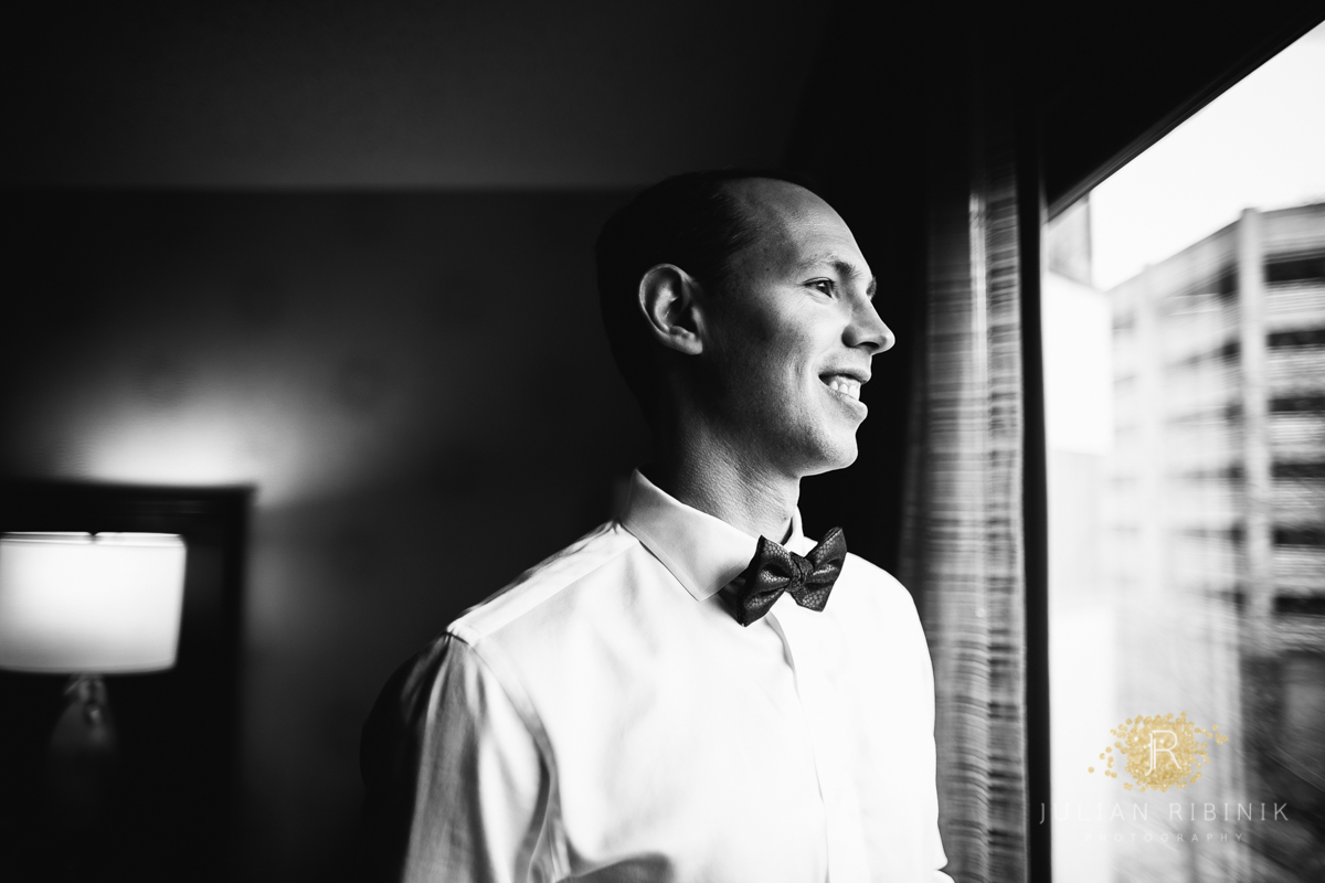 A black and white photo of the groom at a hotel room in NY