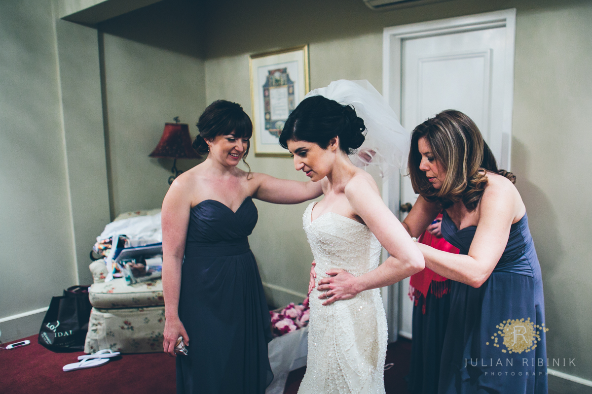 Bride's mother and friends help her put on the wedding gown