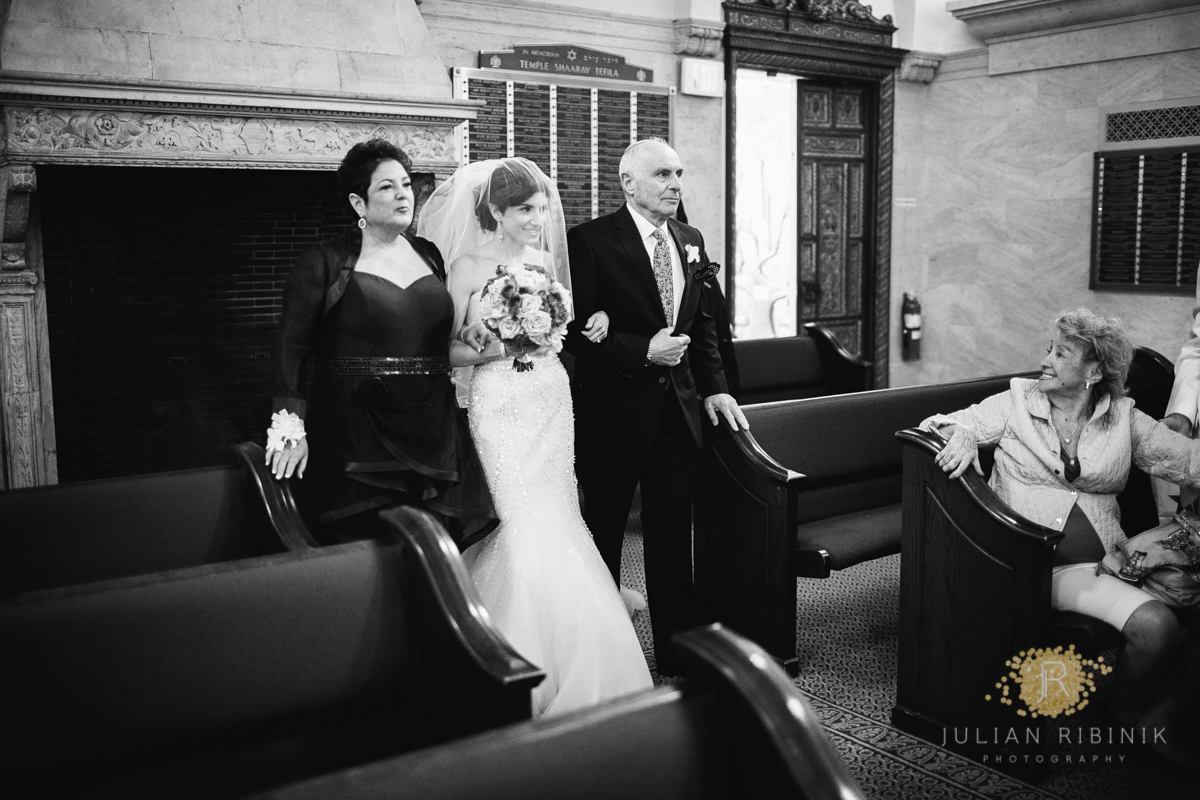 The bride along with her father and mother walks the aisle