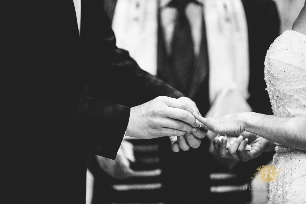 A macro shot of groom putting wedding ring