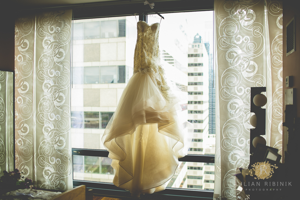 A bridal dress hanging up in front of a window in a Philadelphia hotel room
