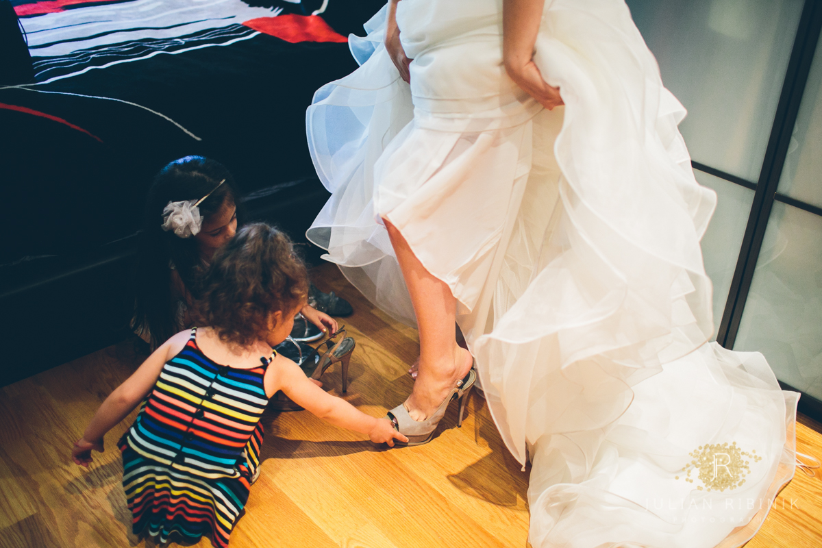 The flower girls help bride to put on the bridal sandals