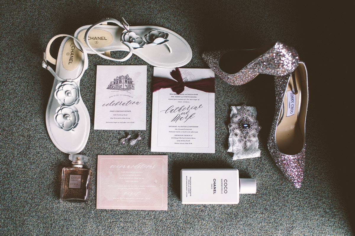 Chanel and Jimmy Choo shoes next to wedding invitations and perfume