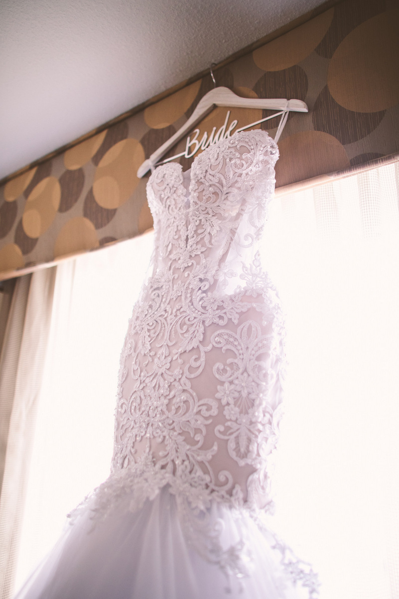 A bridal dress hanging up in front of a window in a NJ hotel room