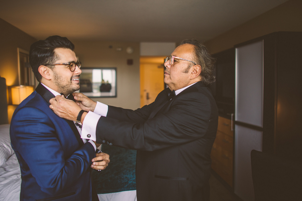 The groom's father helps to fix a bowtie