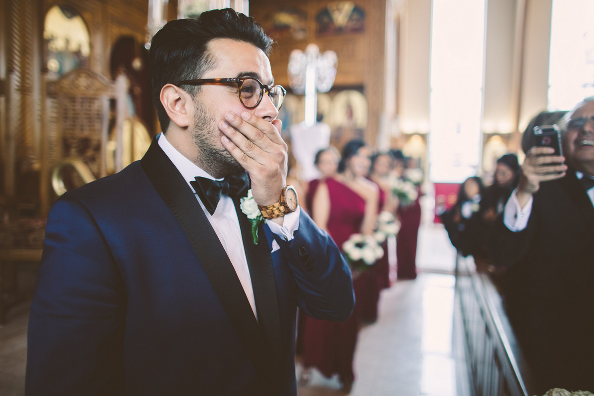 The groom can't contain his smile as the bride walks down the aisle