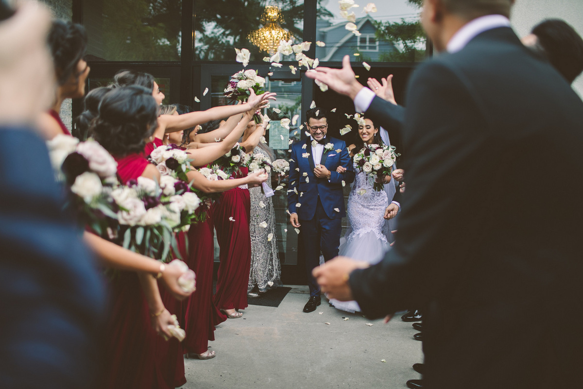 Guests toss rose petals at the happy couple as they leave the church