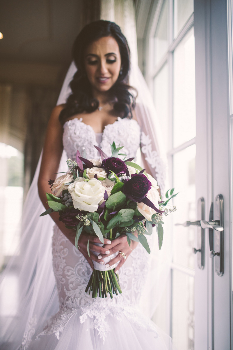 The bride smiles as she gazes down at her wedding flowers