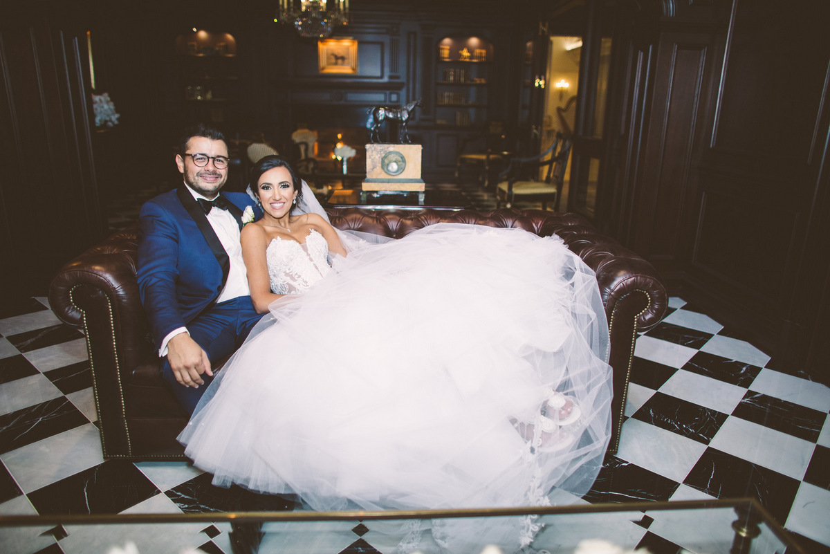 The groom and bride pose together on a leather couch