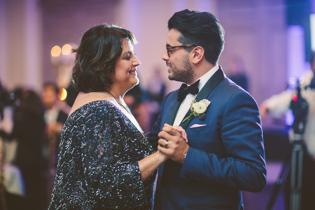 The groom's mother smiles as they dance together