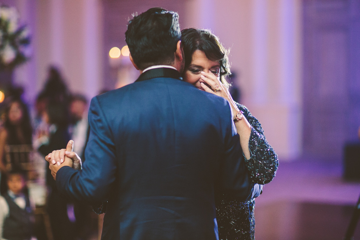 The groom whispers to his mother while they dance