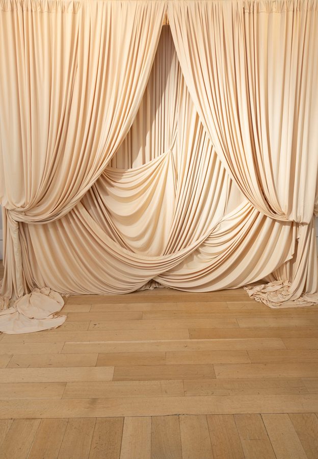 The champagne draped portrait installation standing empty on a wood floor before guests arrived
