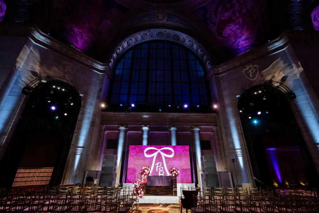 Bat Mitzvah ceremony stage at Cipriani 25 Broadway, arched Palladian window with LED backdrop and gold chairs