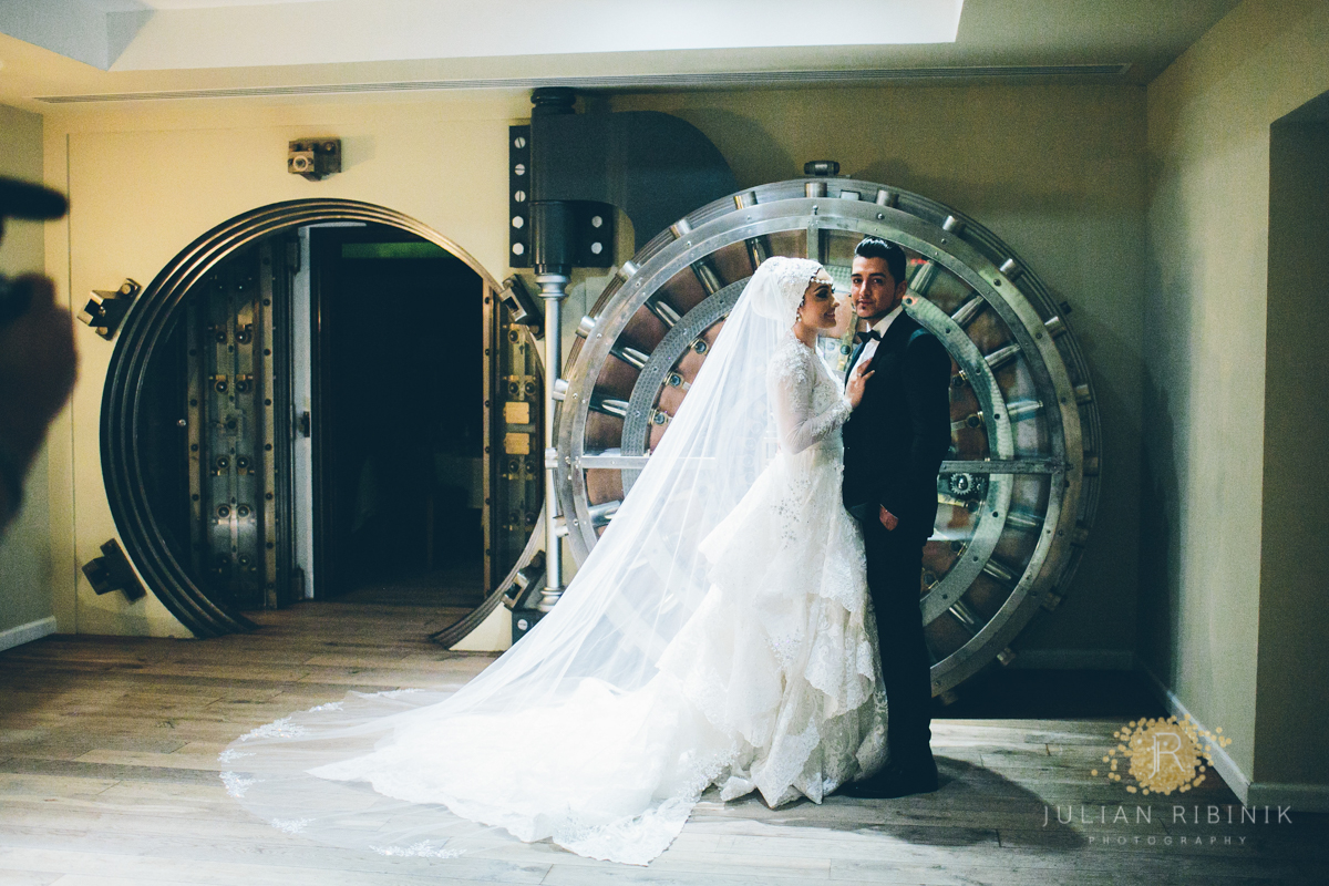 Couple embracing in front of the circular steel vault door at Cipriani Wall Street
