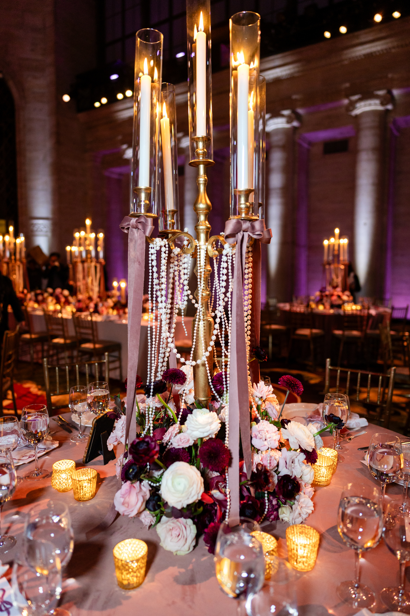 Tall candelabra and low florals on a dining table at Cipriani 25 Broadway between the columns