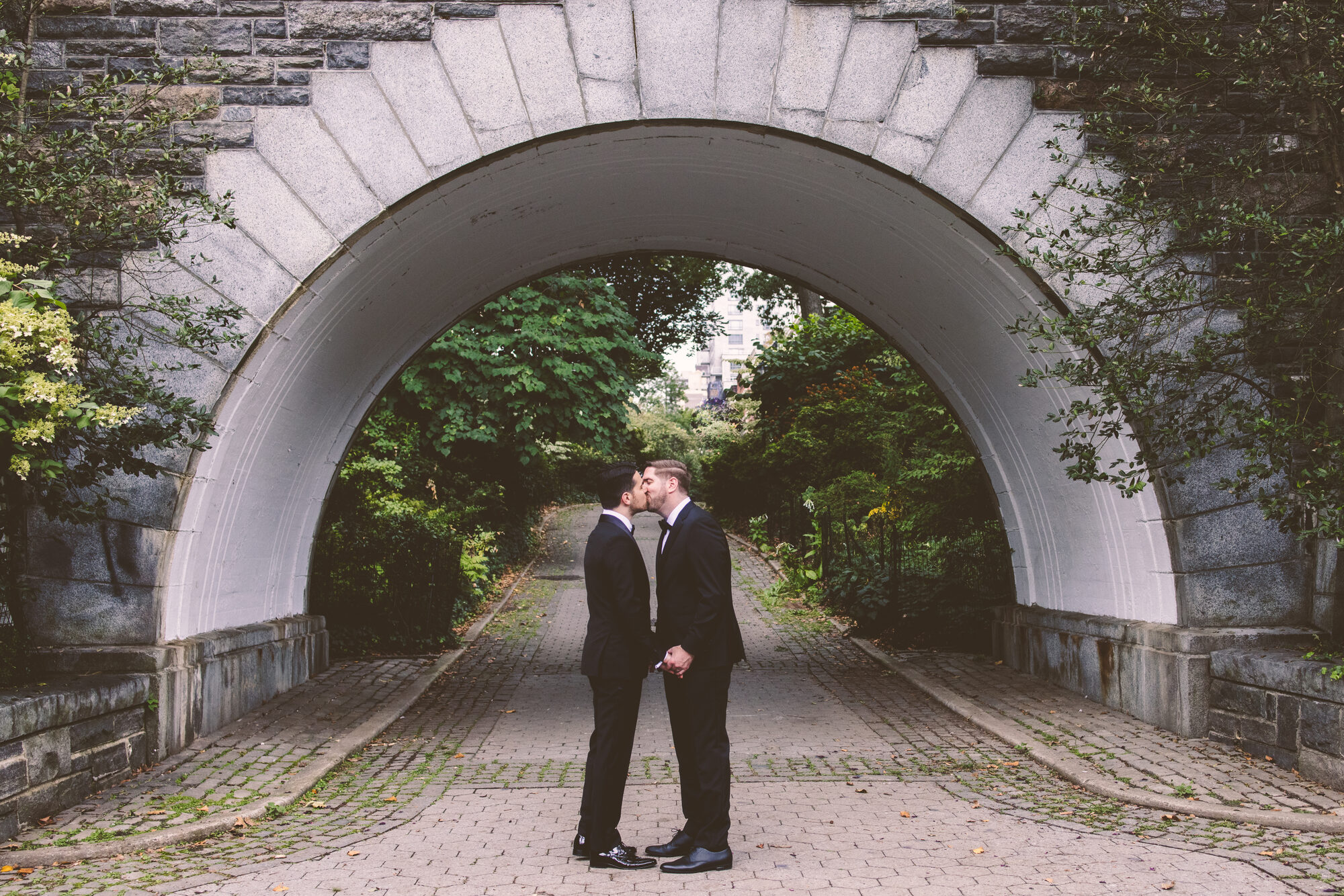 The couple framed by an arched stone passage on their wedding day