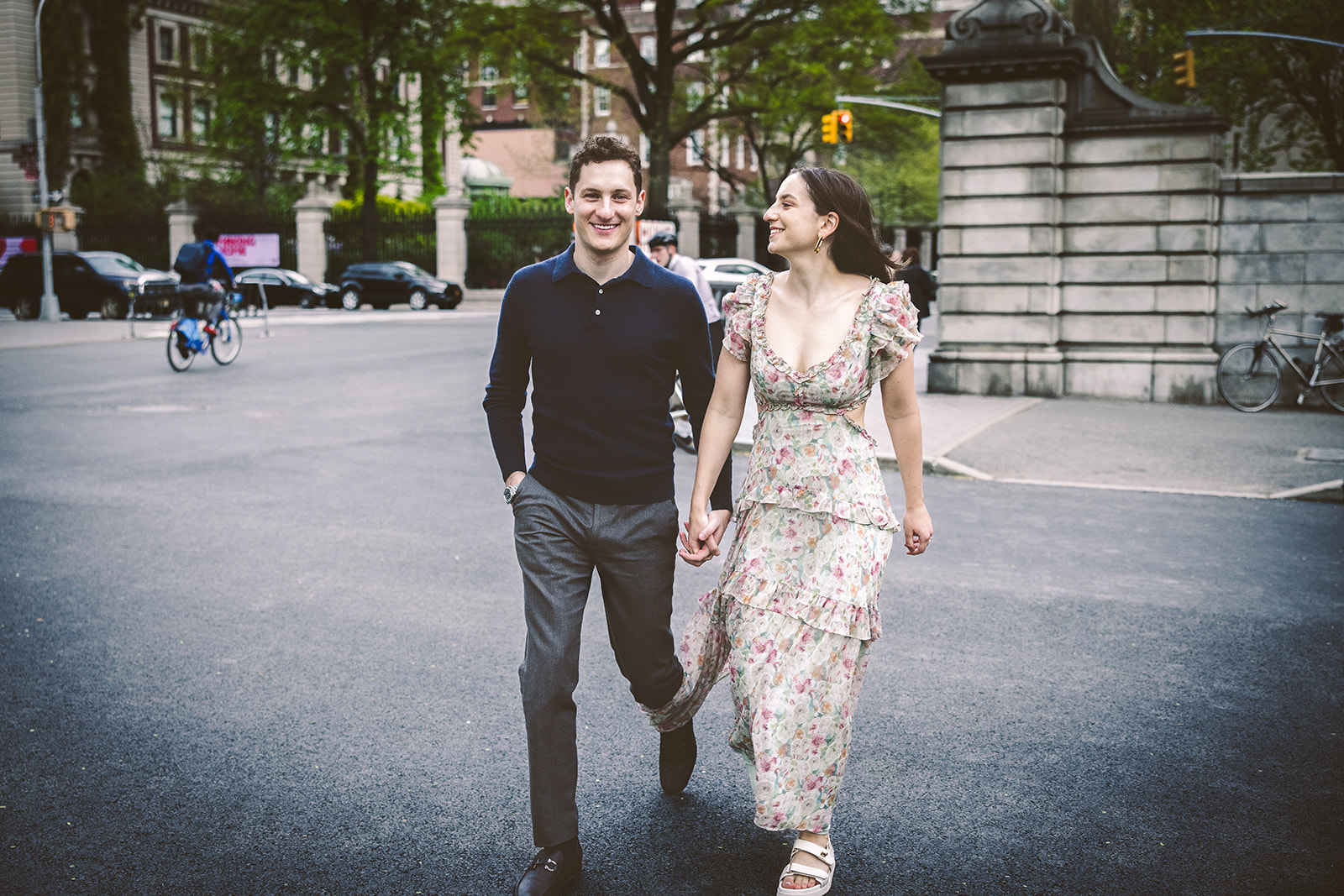 Couple walking hand in hand on a tree-lined Manhattan street in daylight.