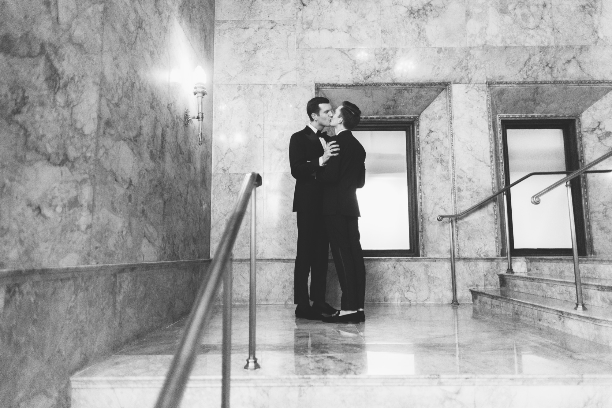 Black and white portrait of a couple embracing in the marble entry hall