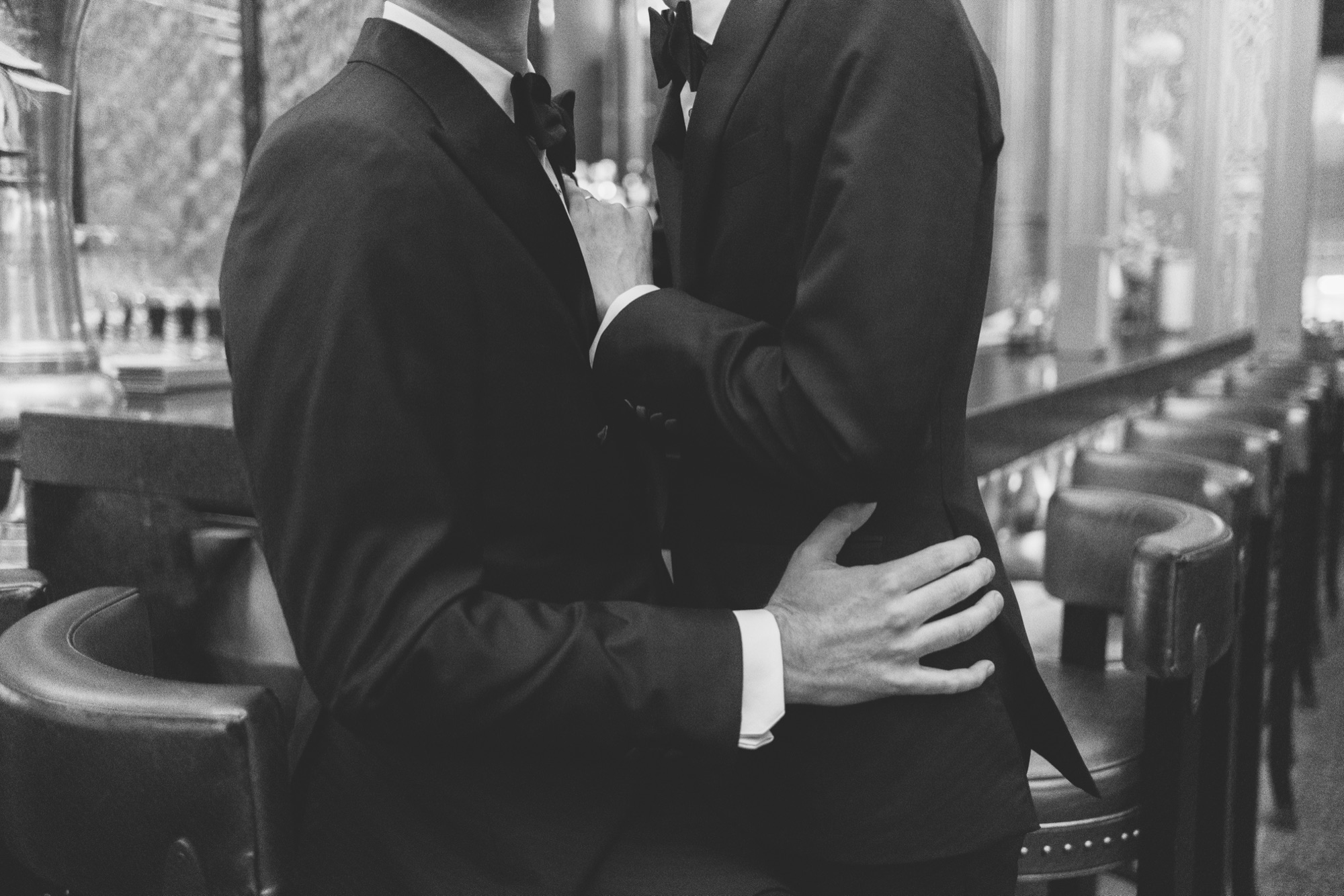 Black and white portrait of a couple holding each other in a panelled corridor