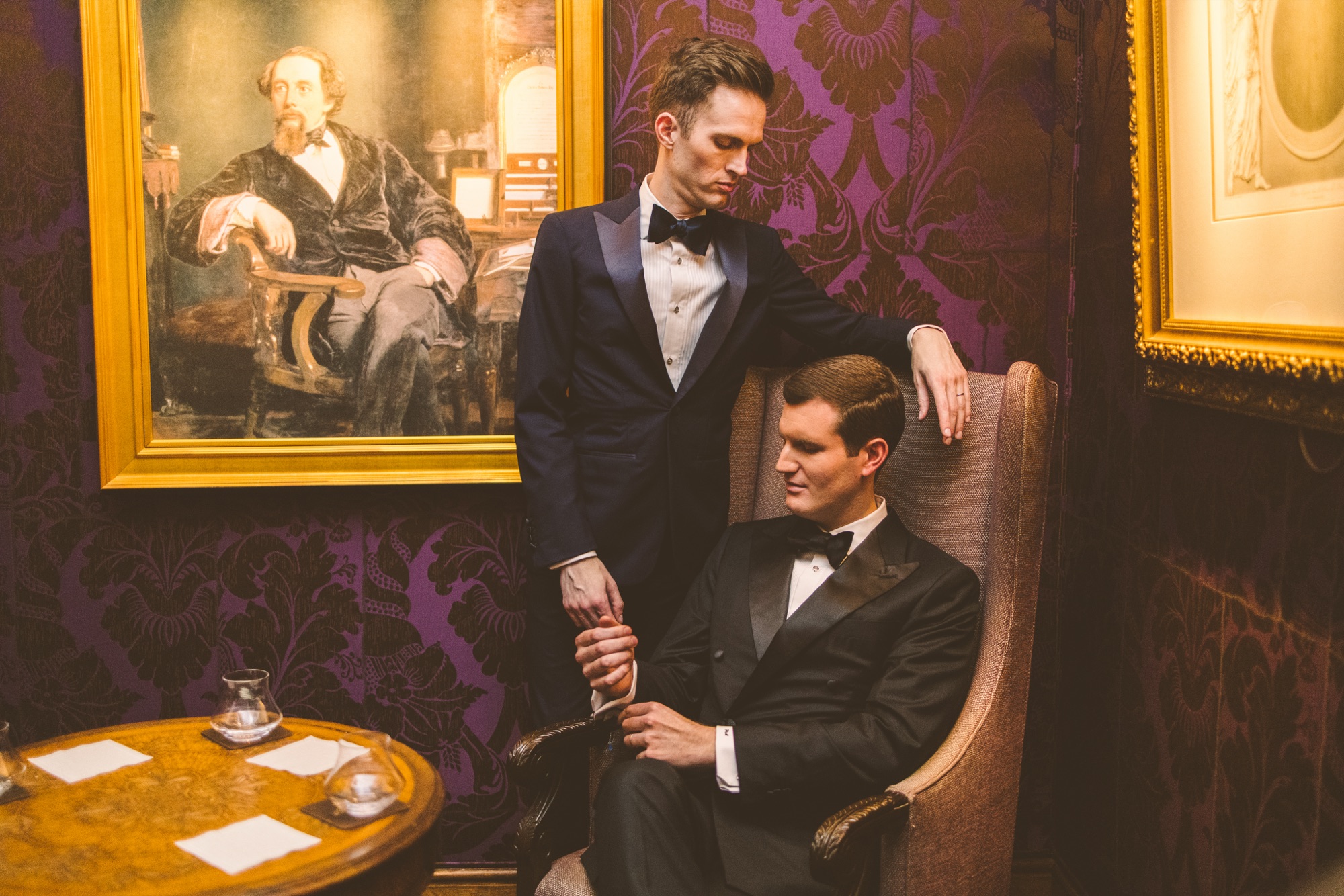 A couple beside an oil portrait on a deep plum coloured wall