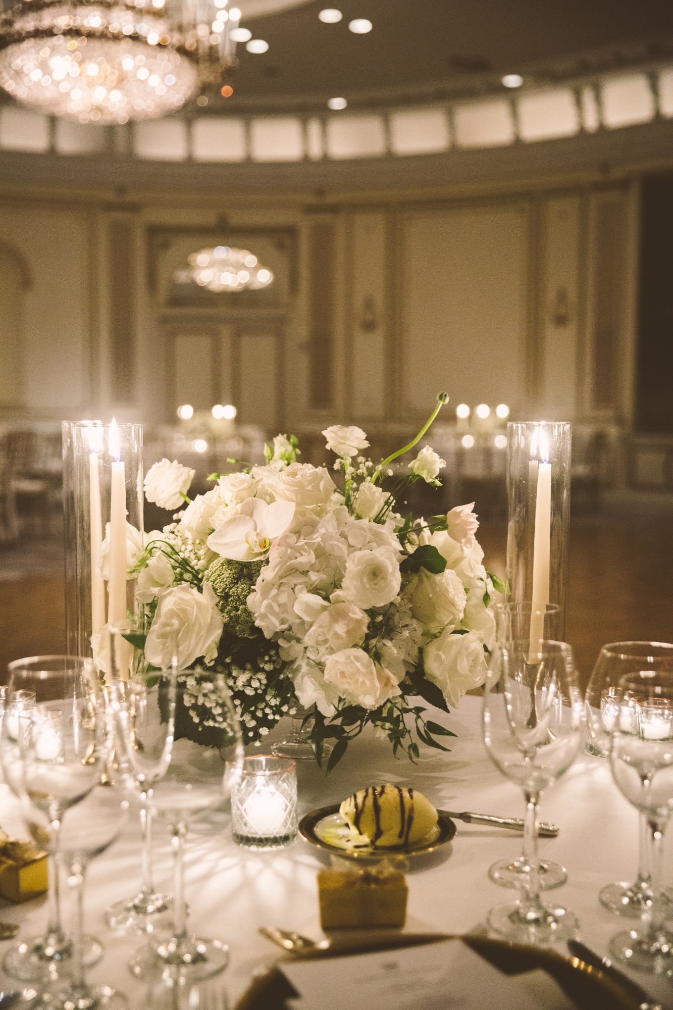 A reception table set with white florals, tapered candles and crystal