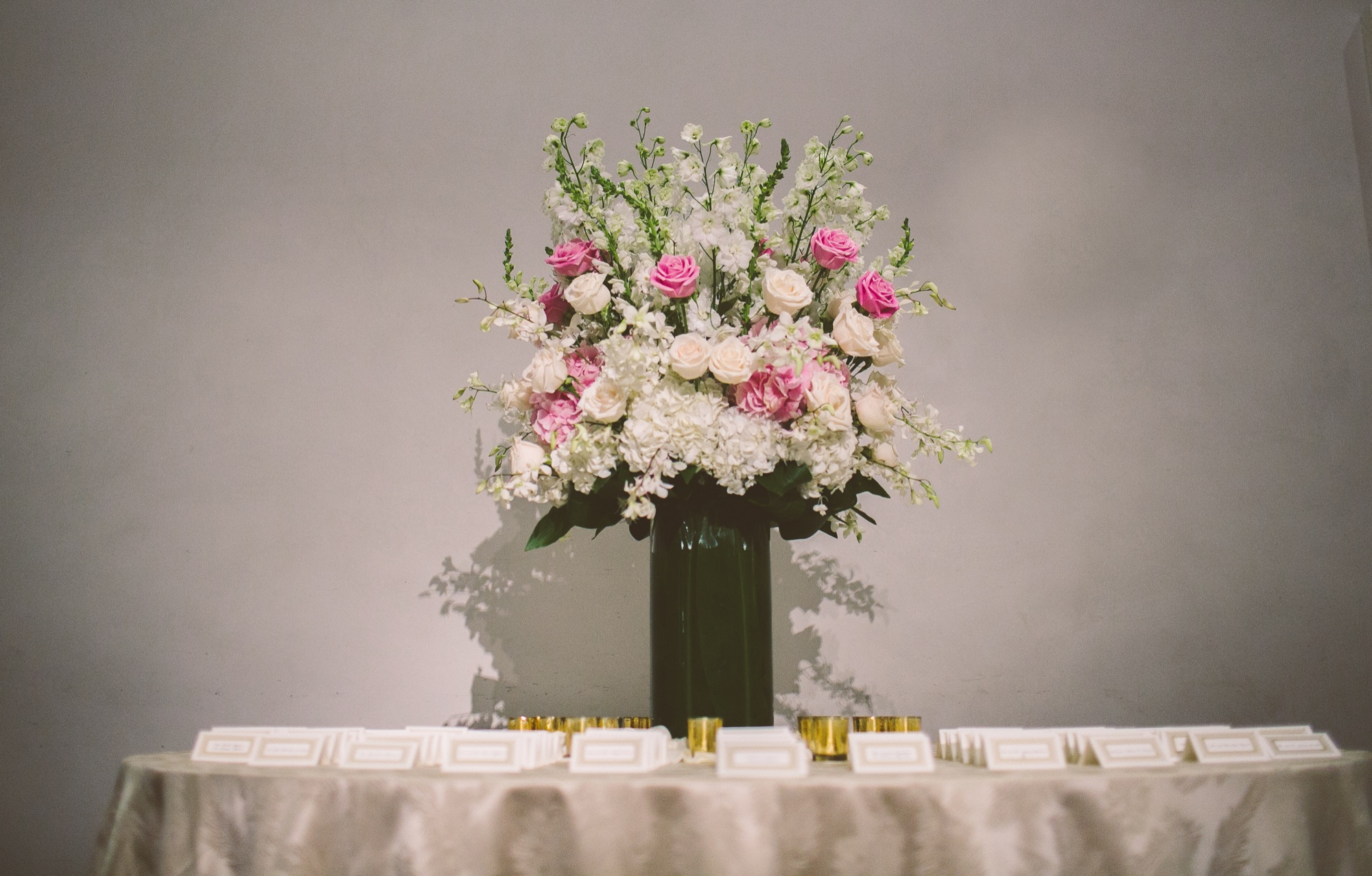 A tall arrangement of pink and white roses on the escort card table
