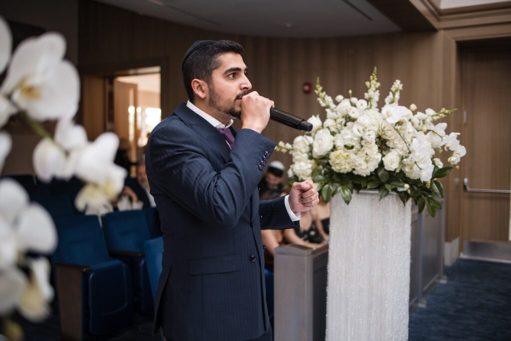 The cantor walking the aisle with a handheld microphone to open the processional