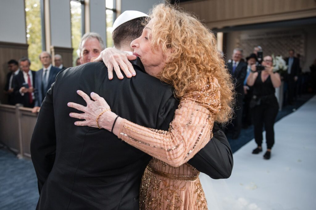 The bride's parents holding each other after walking her to the chuppah