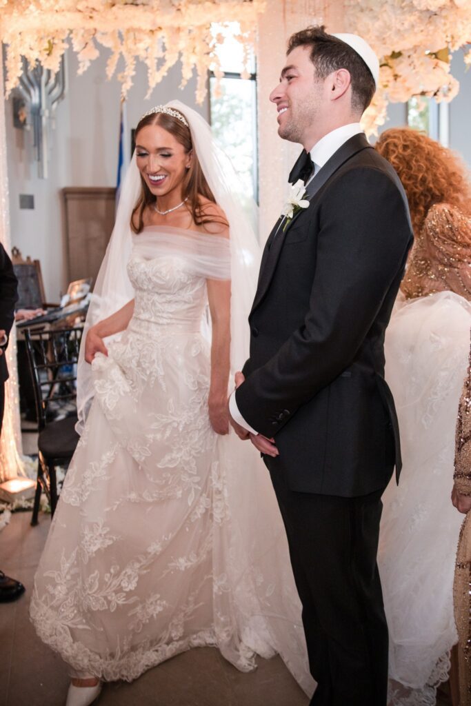 Kinneret and Gordon standing together under the chuppah at their Ohel Yaacob wedding