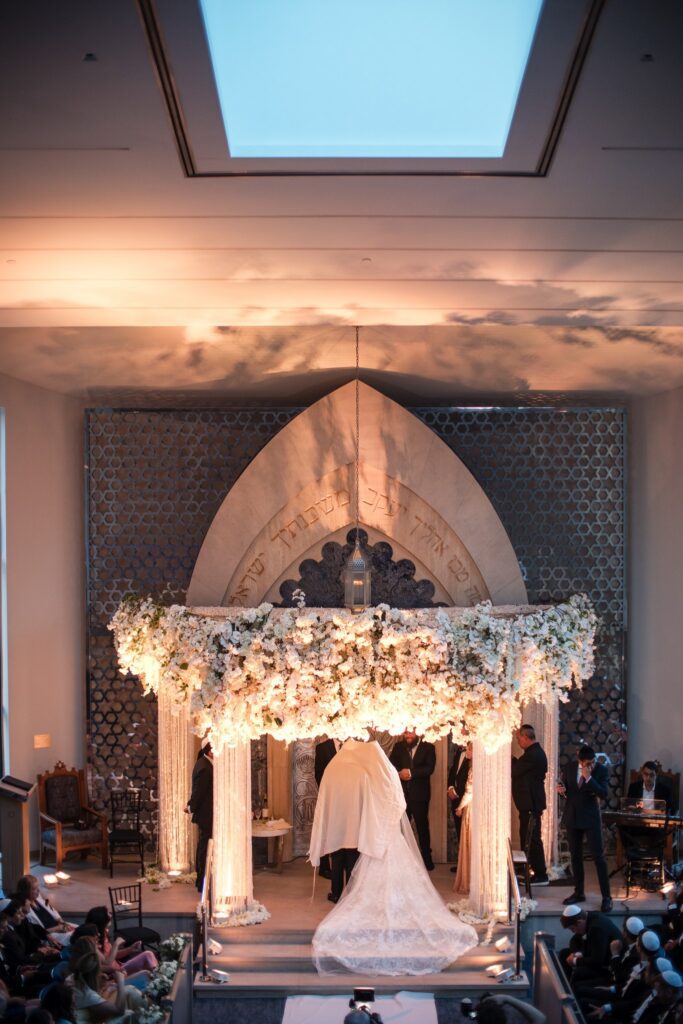 The lit chuppah and the bride's train seen from the back of the sanctuary