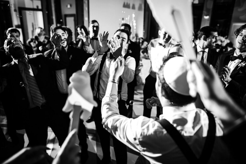 Black and white frame of the men dancing with arms above their heads