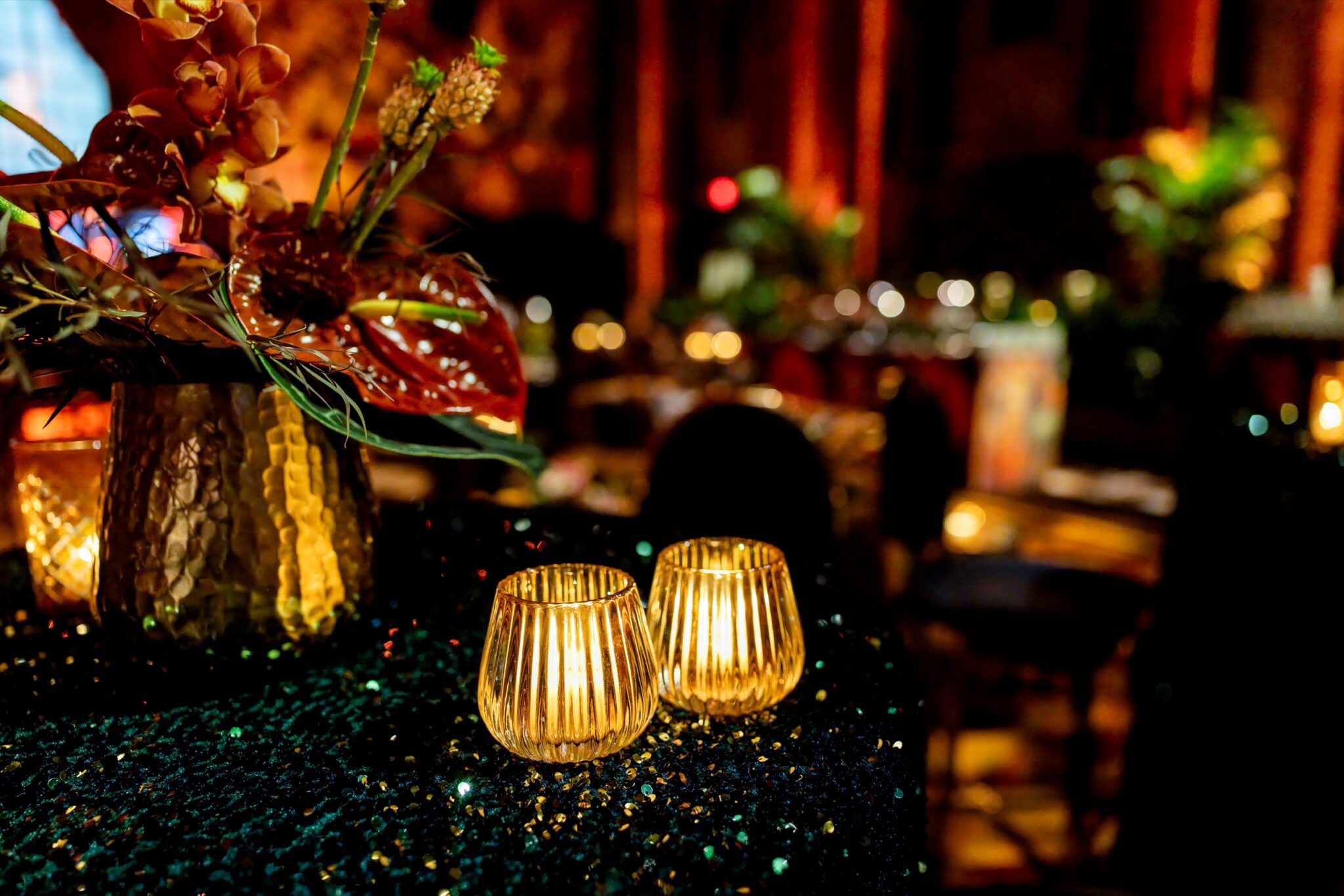 Candlelit floral arrangement on a black sequined table at the Cipriani gala